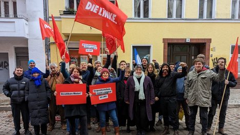 Ein Gruppenfoto mit ca 30 Mitgliedern der LINKEN. Neukölln mit Fahnen und Schildern "Vergesellschaftung jetzt"
