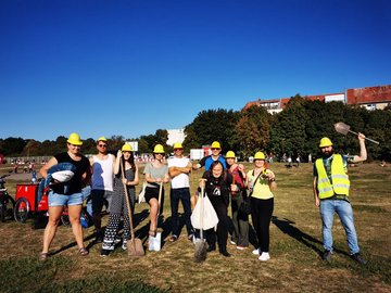 Eine Gruppe Menschen mit Bauhelmen aus und Spaten in der Hand auf dem Tempelhofer Feld